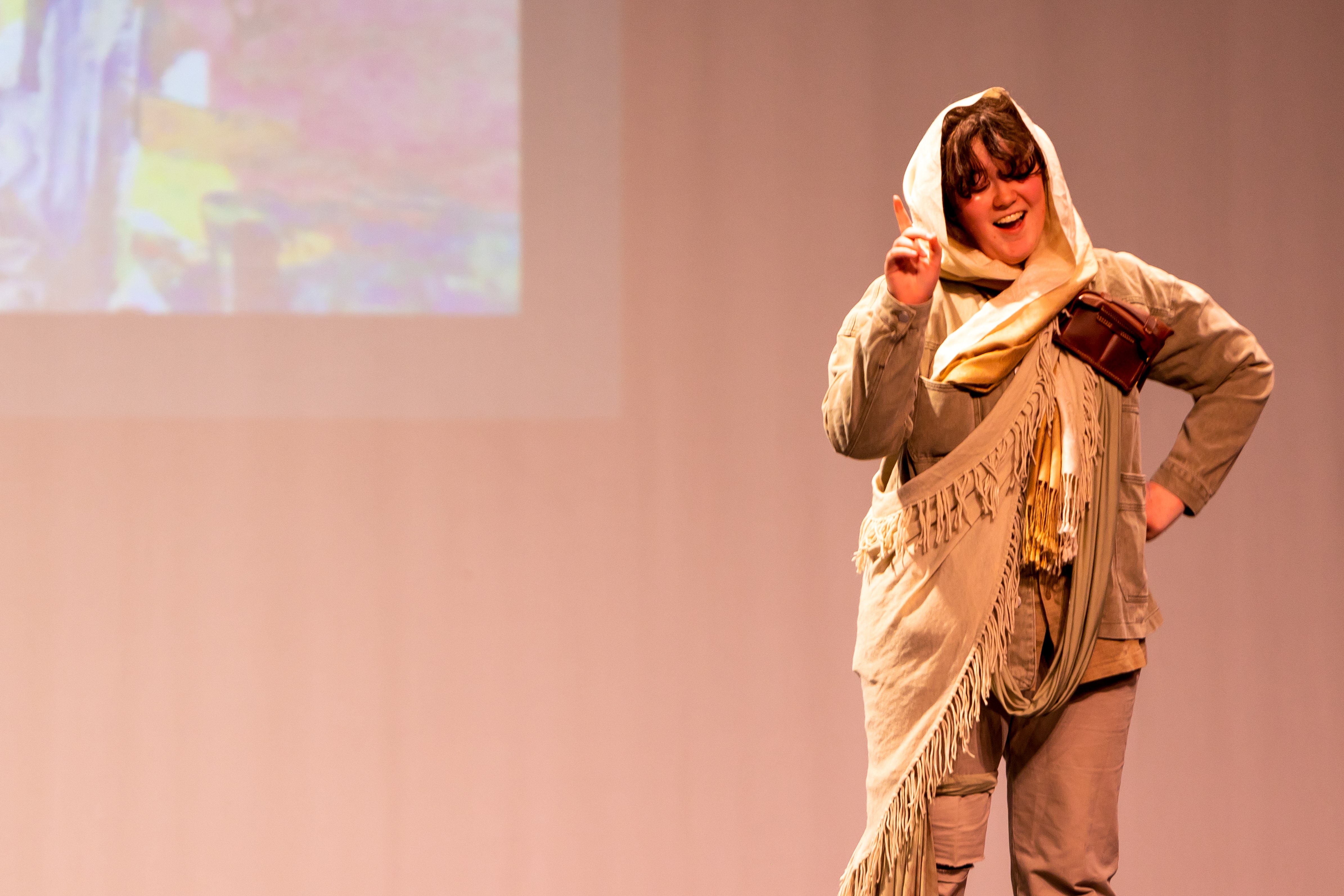 Student in costume performing a dramatic role on stage during a school theatre production