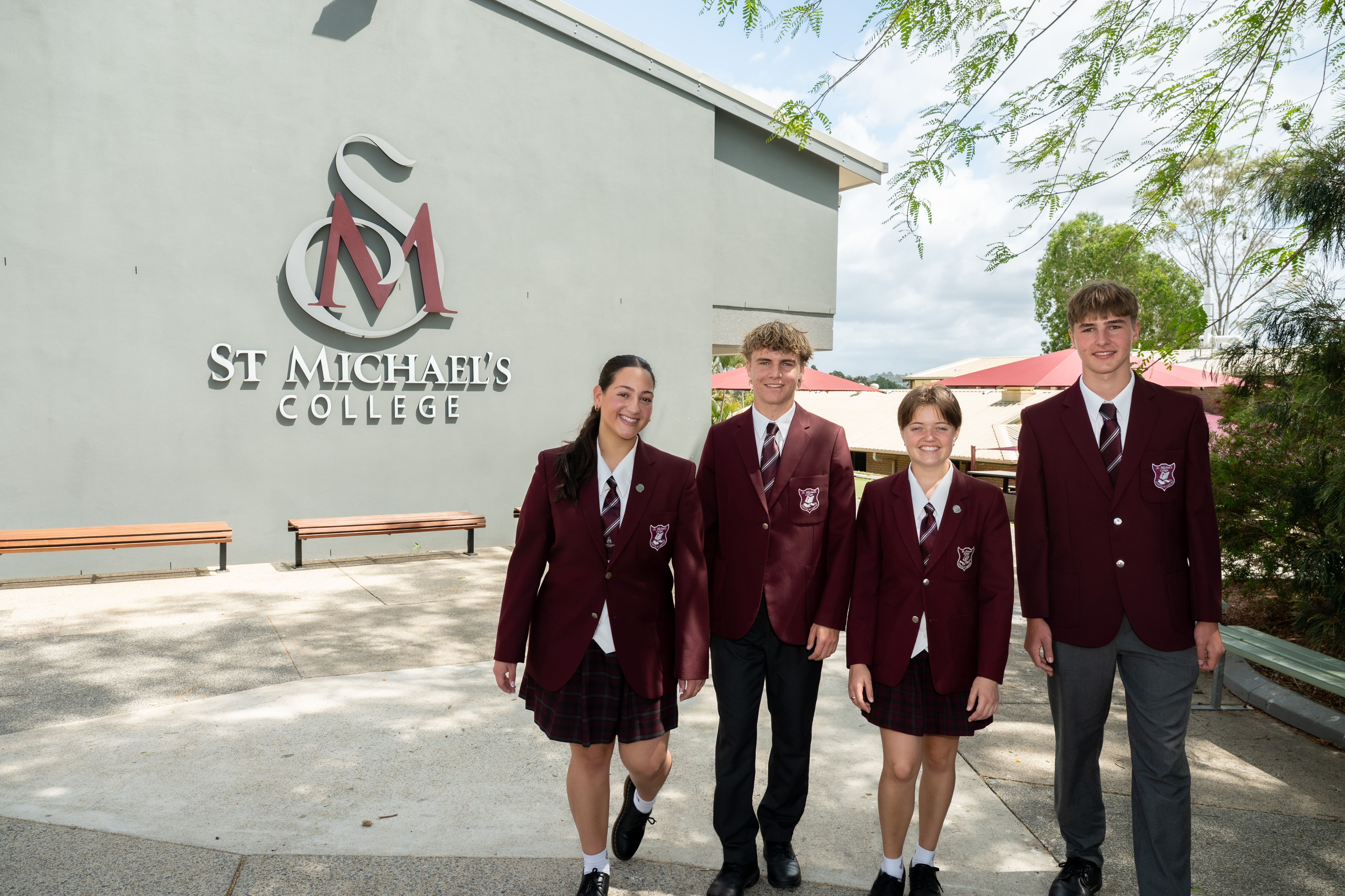 Students in St Michael’s College uniform standing together in front of campus signage displaying the school name and logo