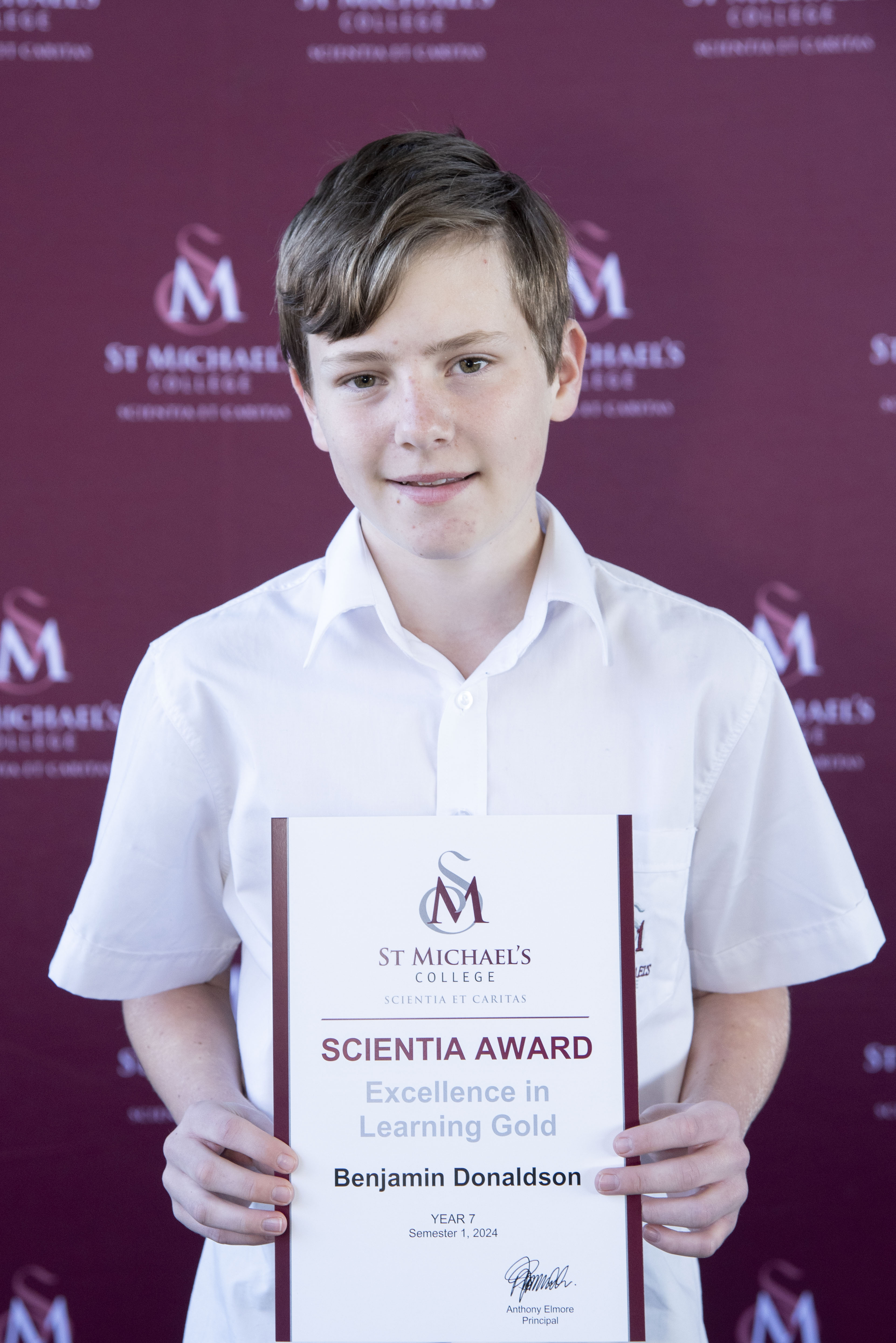 A student holding the Scientia Awards Certificate with a smile