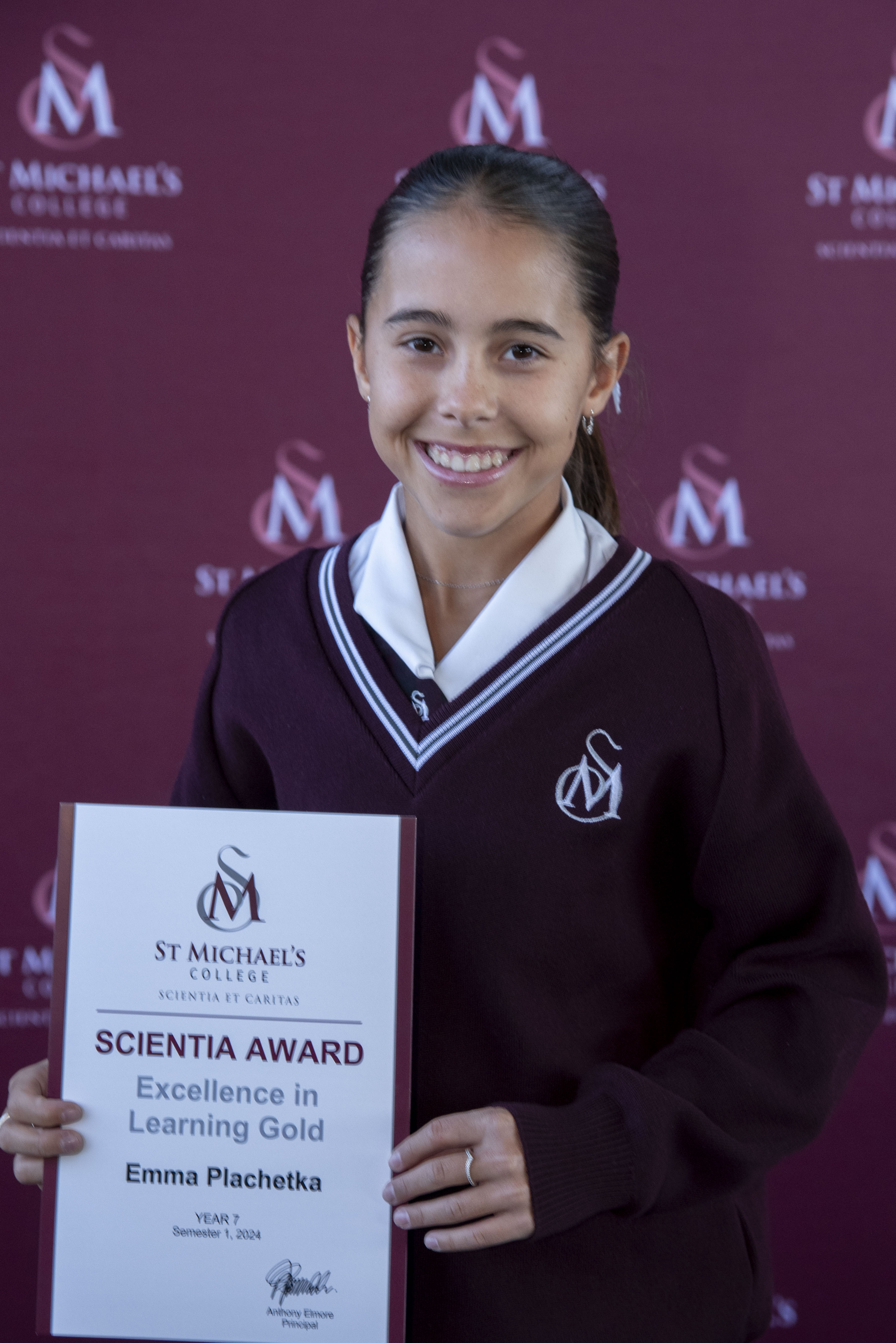 A student holding the Scientia Awards Certificate with a smile