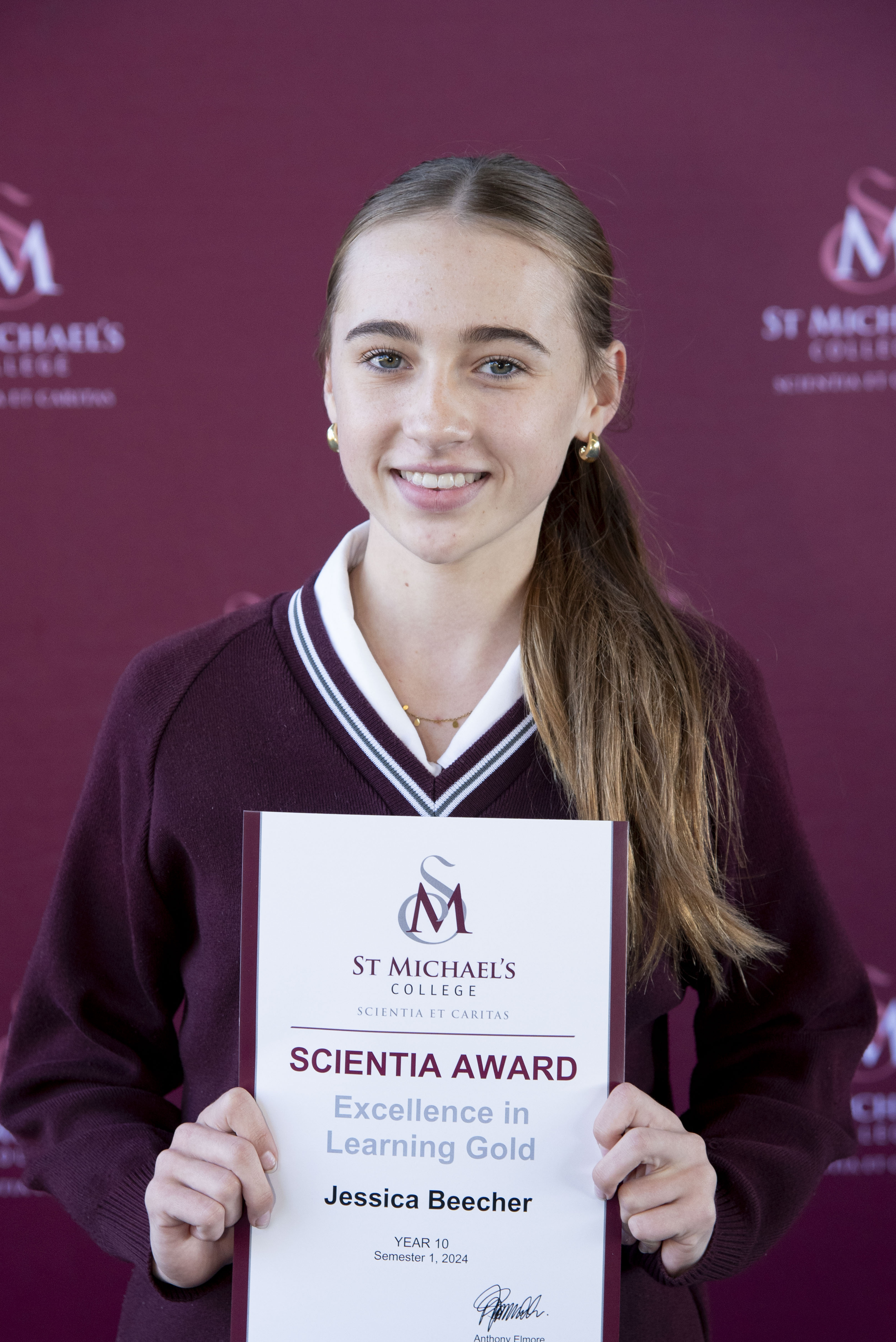 A student holding the Scientia Awards Certificate with a smile