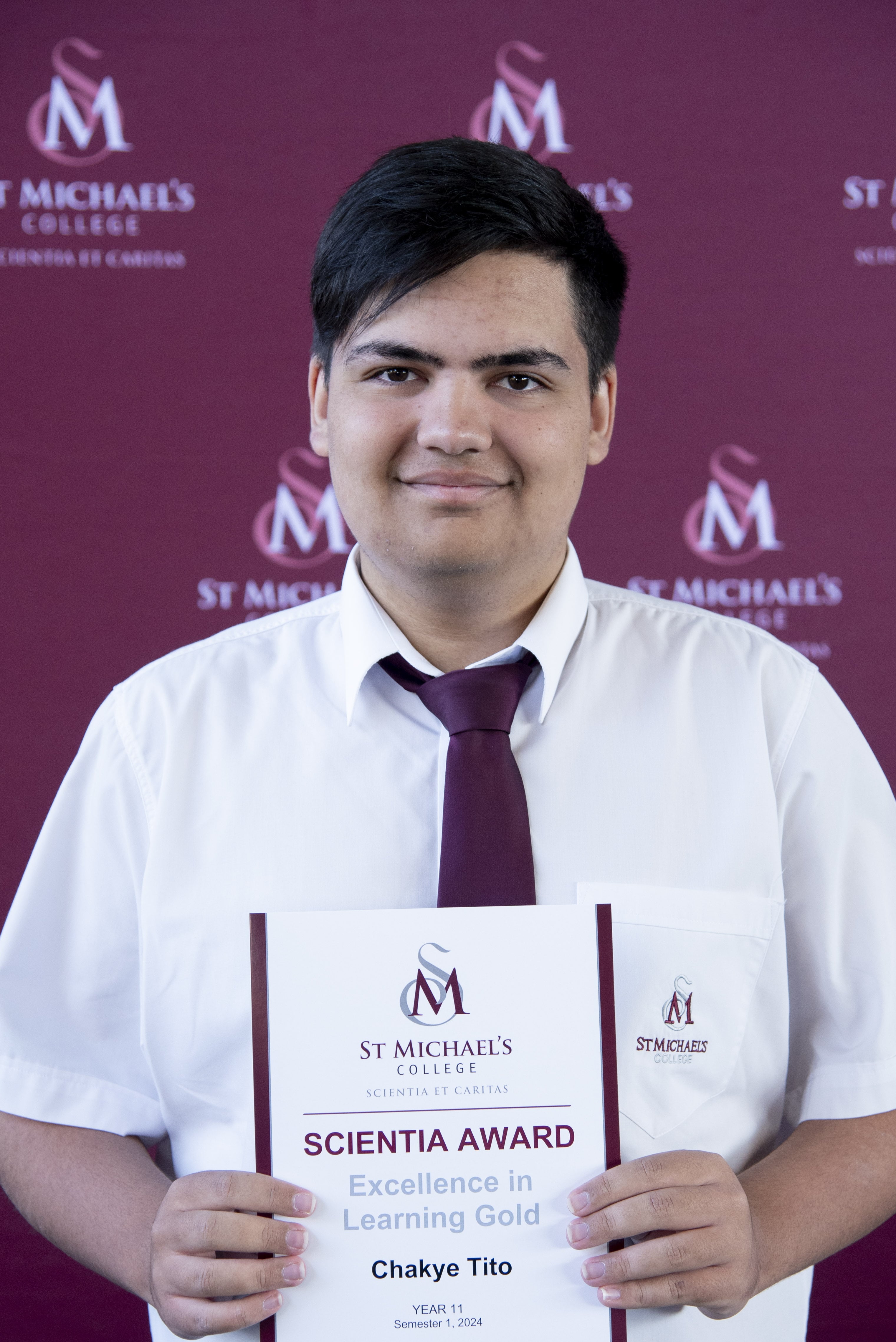 A student holding the Scientia Awards Certificate with a smile