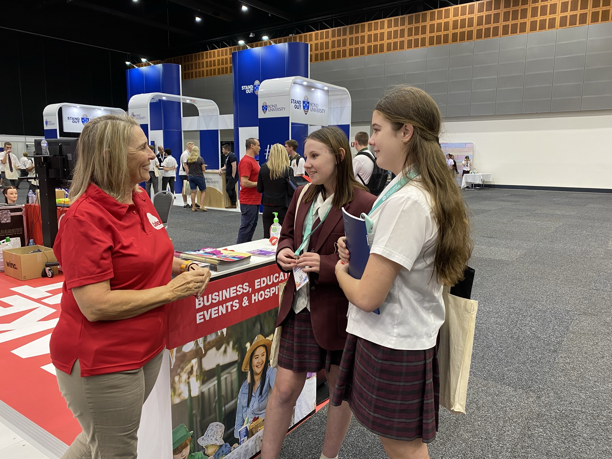Students speaking with a representative at a careers expo booth about business, education and hospitality pathways