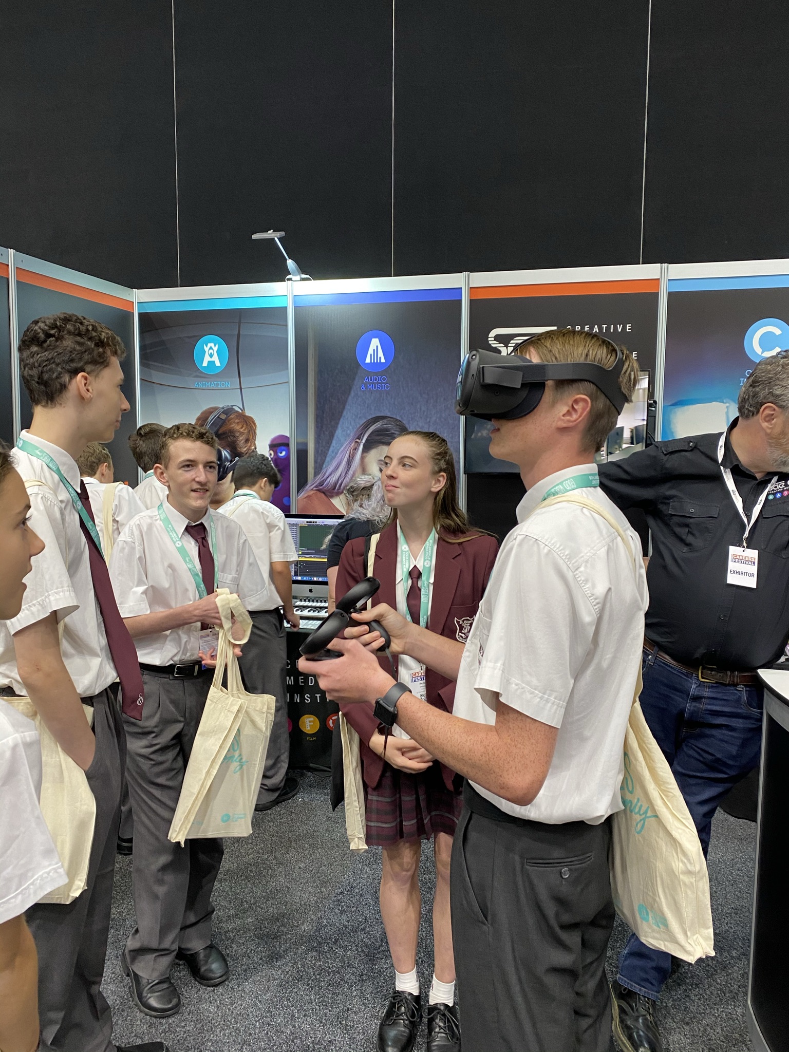 Students participating in a virtual reality activity at a careers expo, using VR headset while others observe at an interactive stand