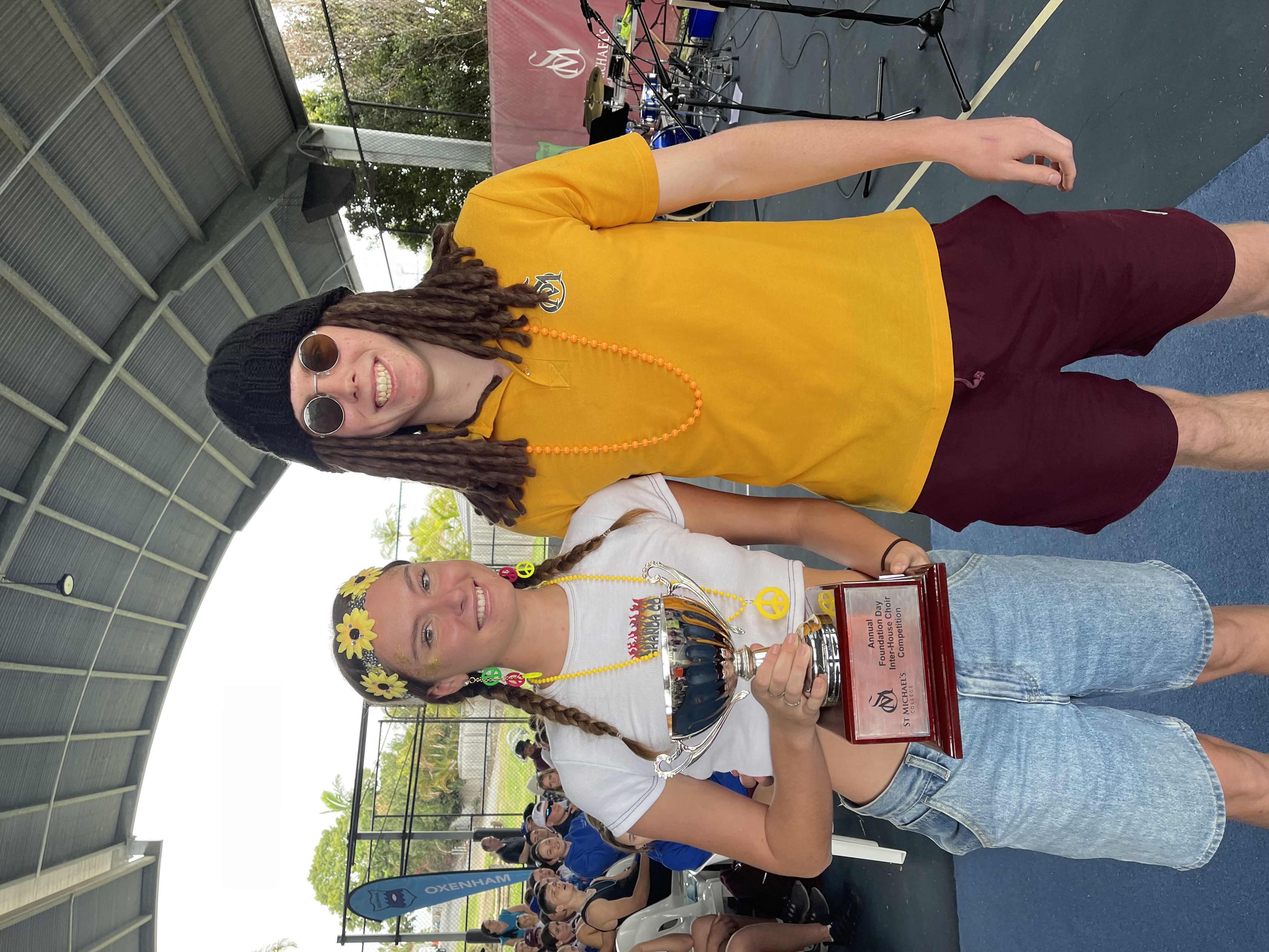 Student holding a winning trophy with the coach