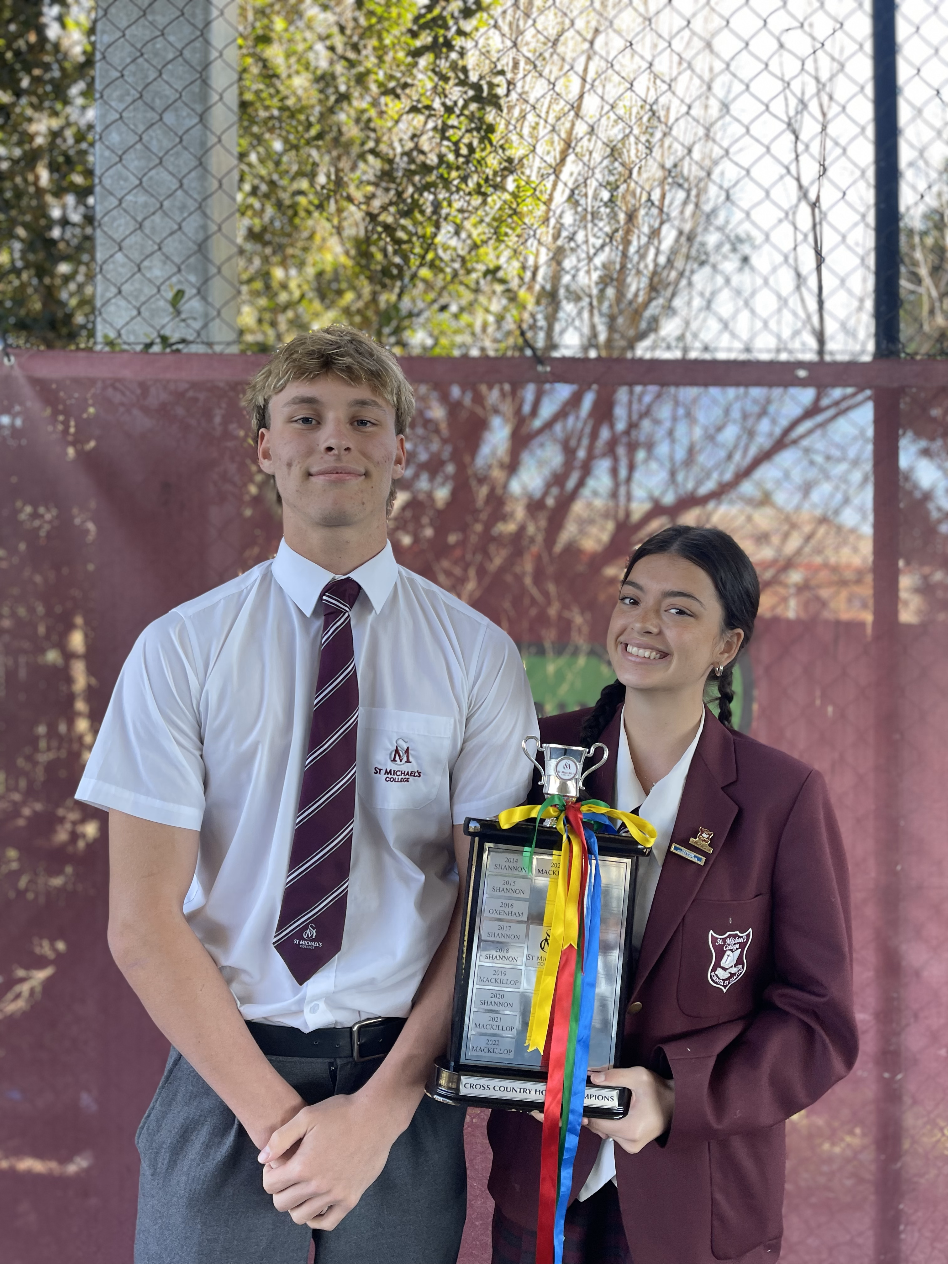 Students holding cross country trophy at school event