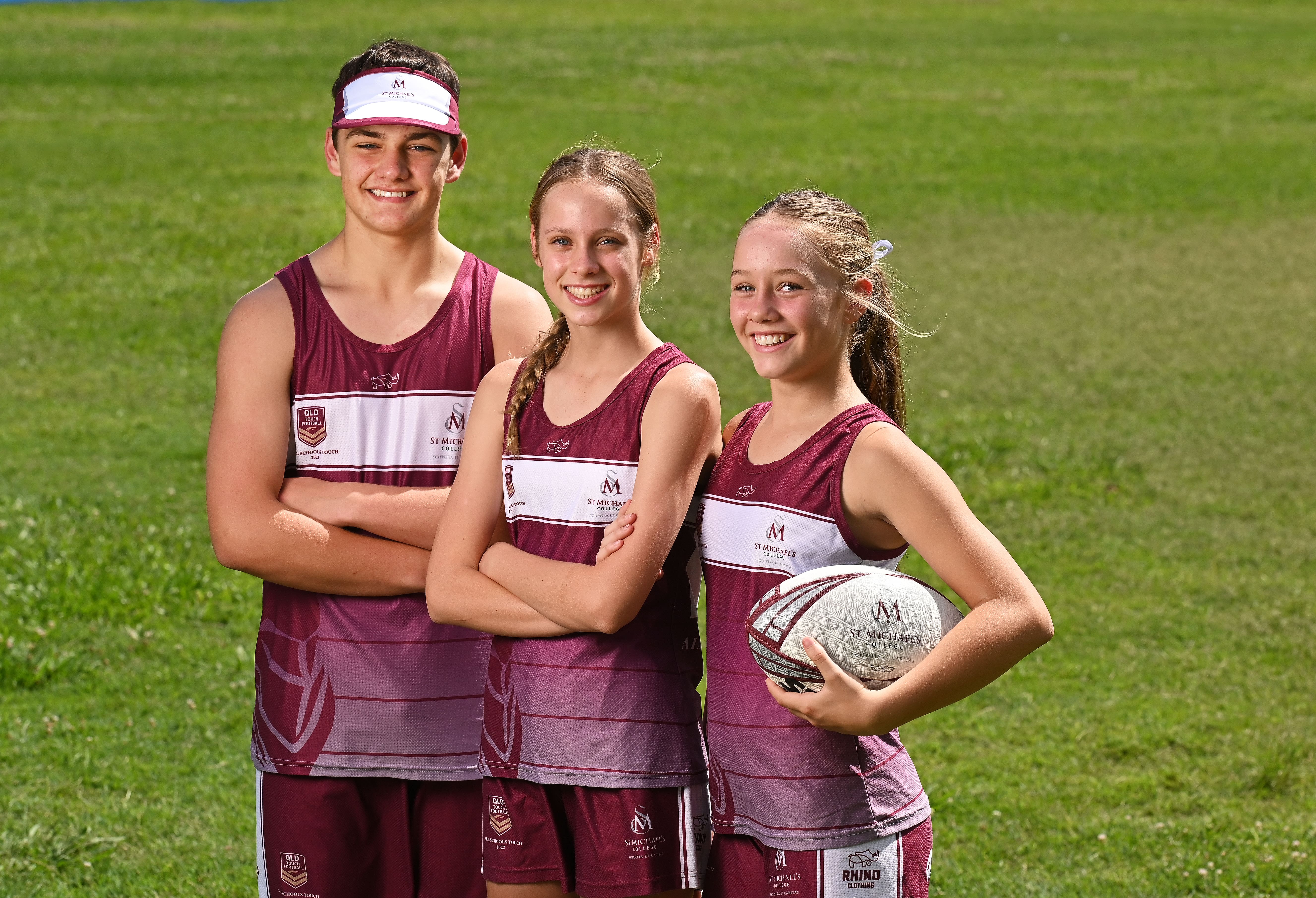 Students in sports uniforms standing together on a field during a team photo
