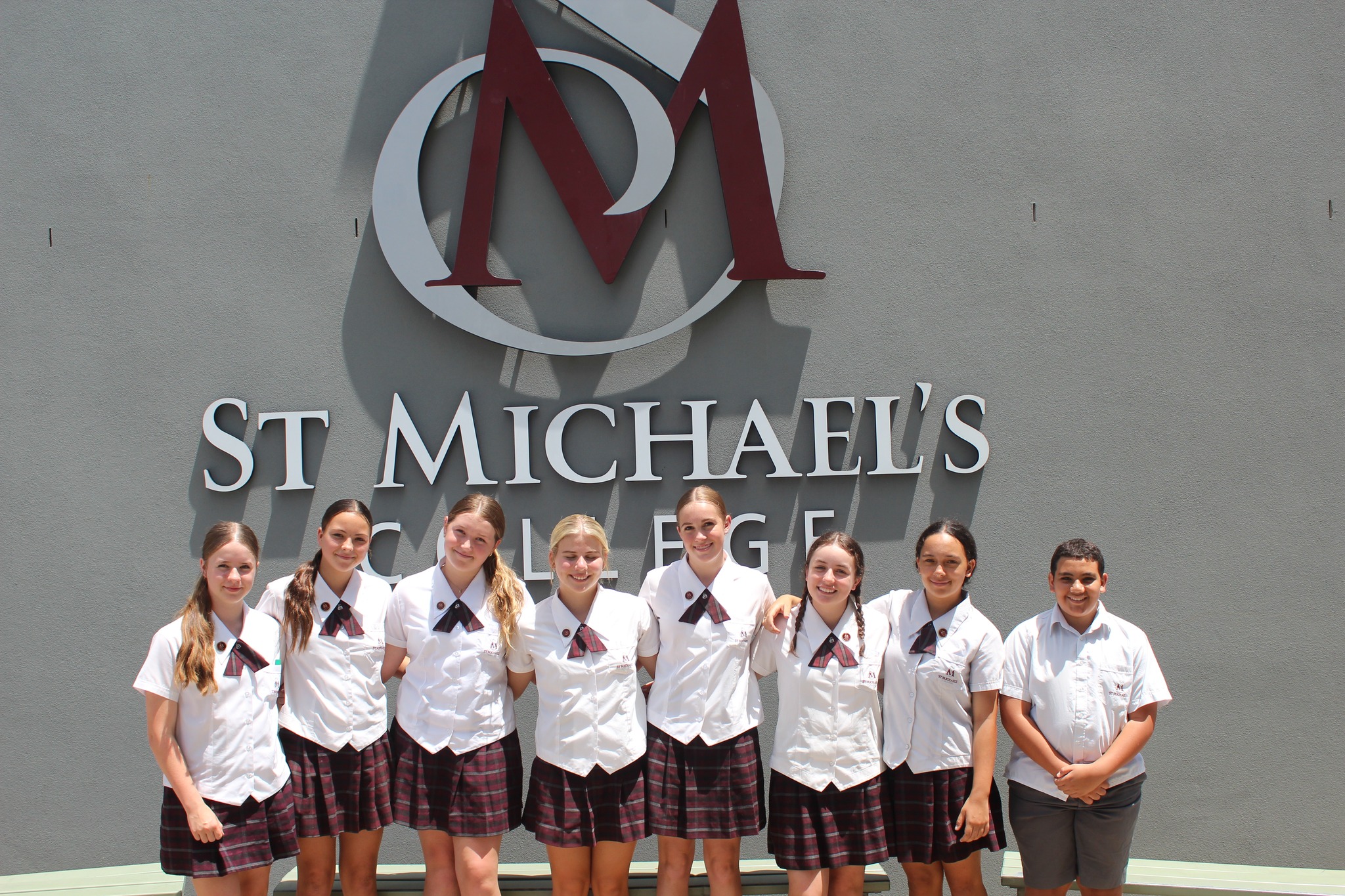 School Year 9 leaders line up in front of the school emblem