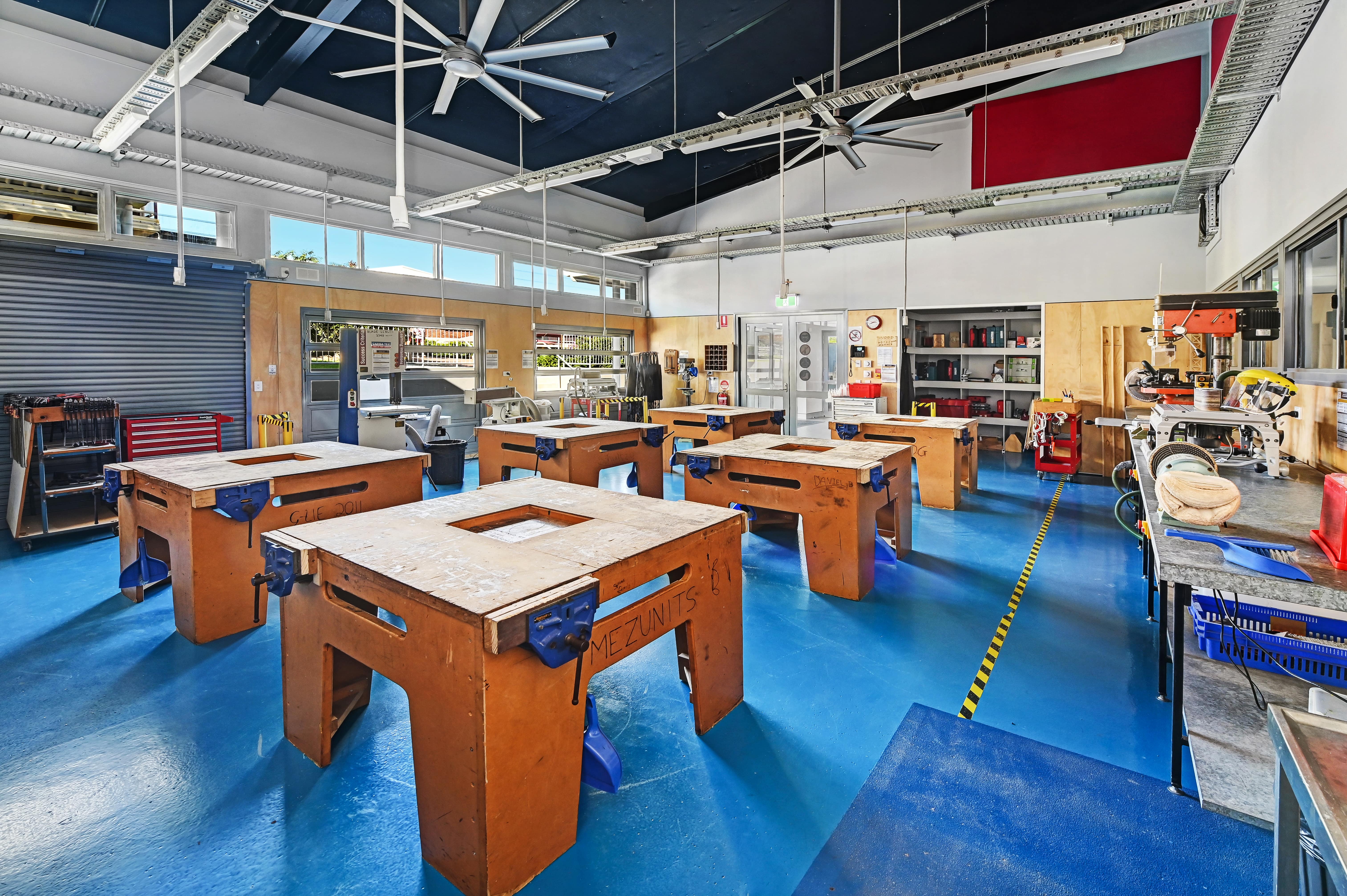 School workshop classroom with wooden workbenches, tools and machinery arranged for practical learning